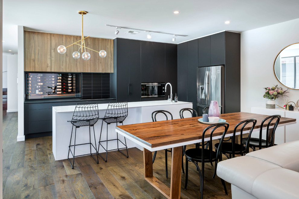 Idées déco pour une cuisine américaine parallèle contemporaine avec des portes de placard noires, une crédence noire, îlot, un placard à porte plane, une crédence en carrelage métro et un sol en bois brun.