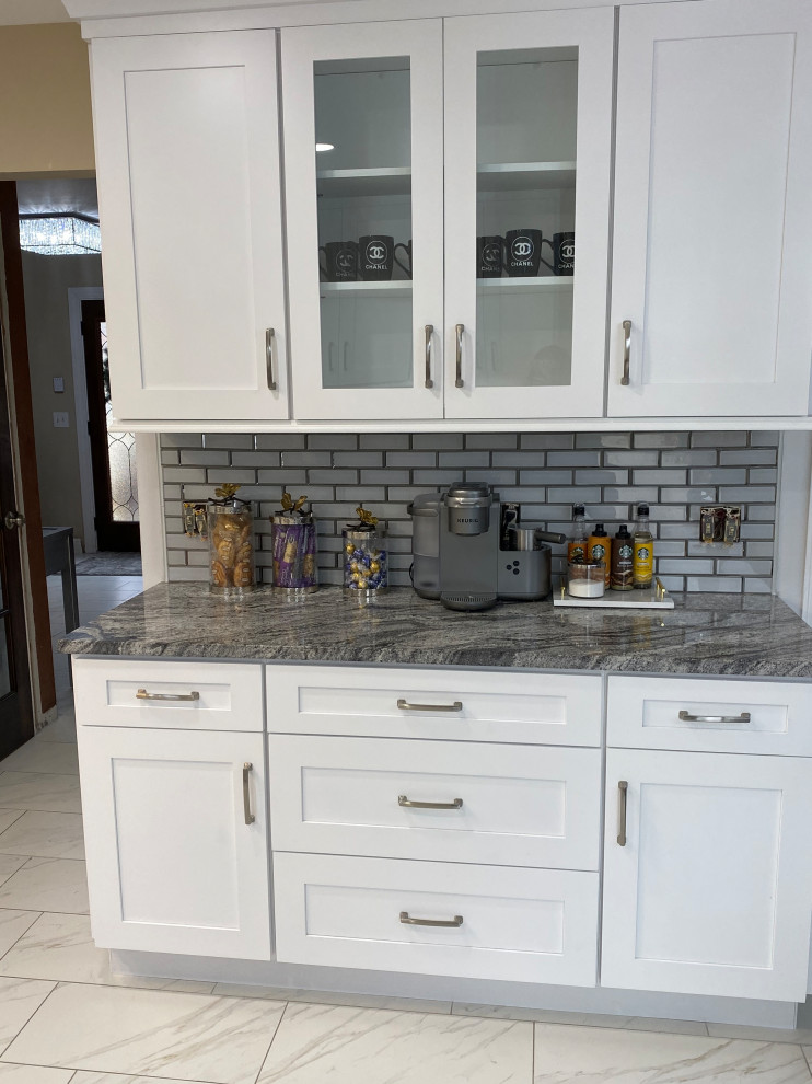 This is an example of a medium sized contemporary u-shaped kitchen/diner in Detroit with a belfast sink, shaker cabinets, white cabinets, granite worktops, grey splashback, metro tiled splashback, marble flooring, no island, white floors and grey worktops.