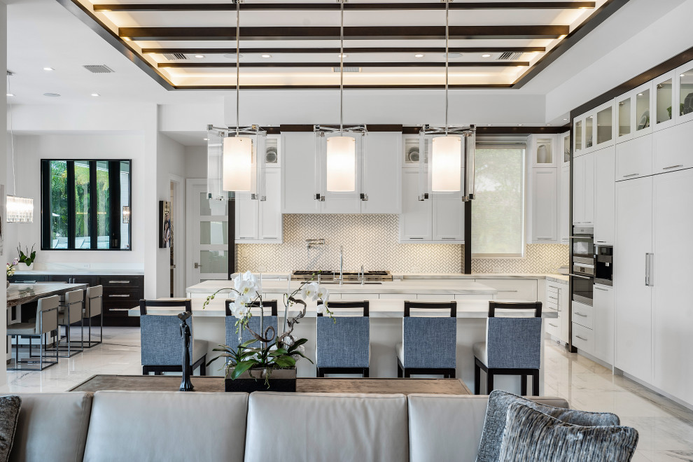 Open concept kitchen - contemporary l-shaped white floor, exposed beam and tray ceiling open concept kitchen idea in Miami with flat-panel cabinets, white cabinets, white backsplash, mosaic tile backsplash, paneled appliances, an island and gray countertops
