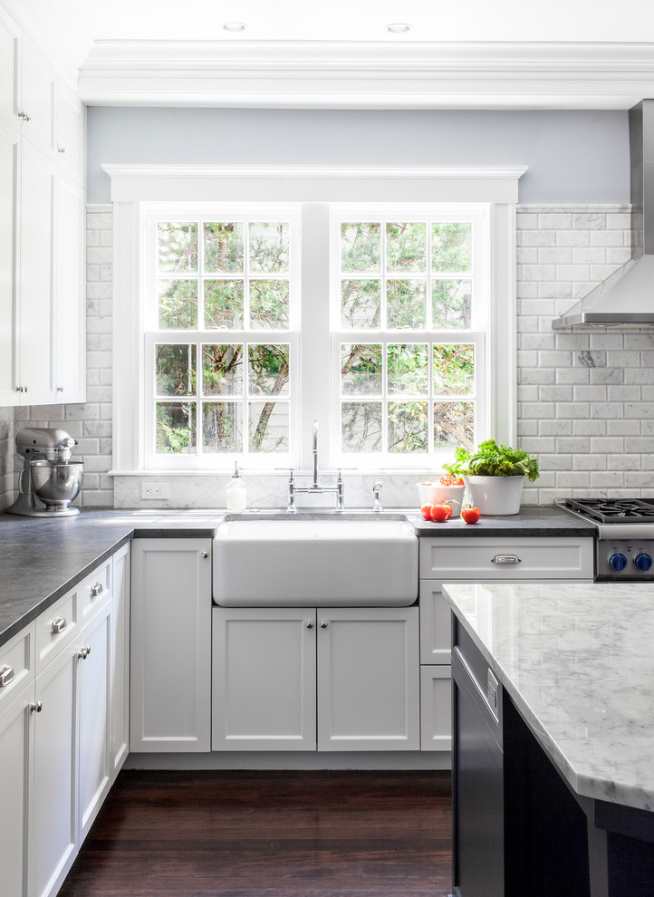 Foto på ett mellanstort vintage kök, med en rustik diskho, luckor med infälld panel, vita skåp, granitbänkskiva, grått stänkskydd, rostfria vitvaror, mörkt trägolv, en köksö och stänkskydd i marmor