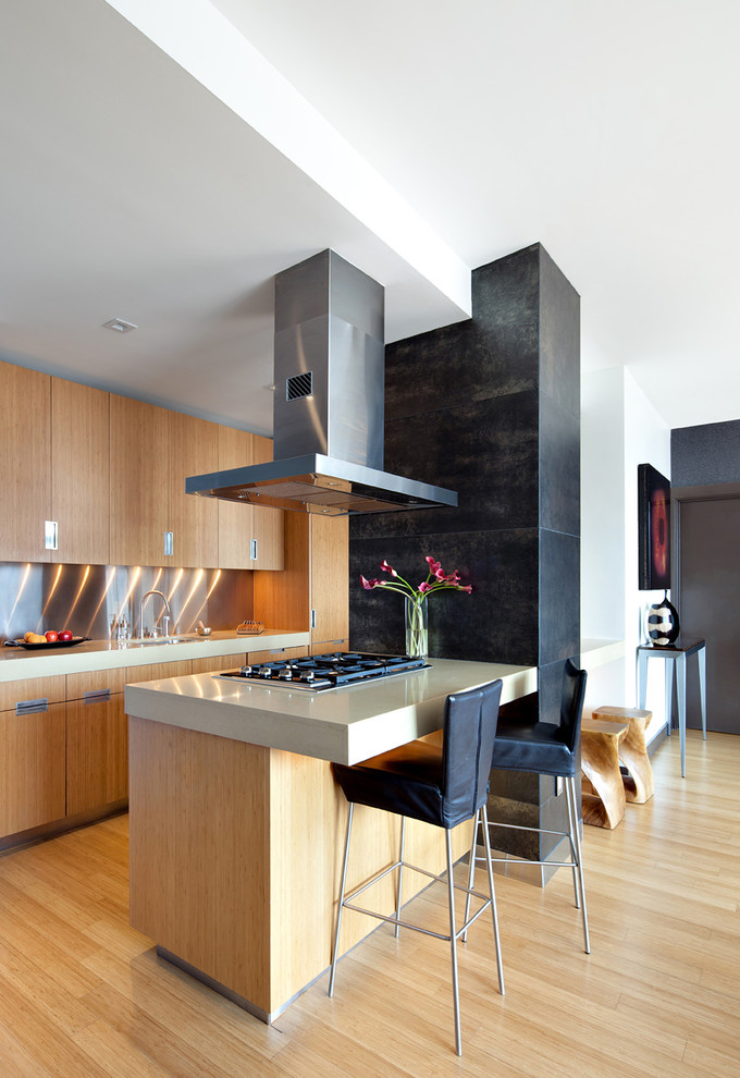Modern inredning av ett mellanstort kök, med släta luckor, skåp i ljust trä, stänkskydd med metallisk yta, en undermonterad diskho, mellanmörkt trägolv och en köksö