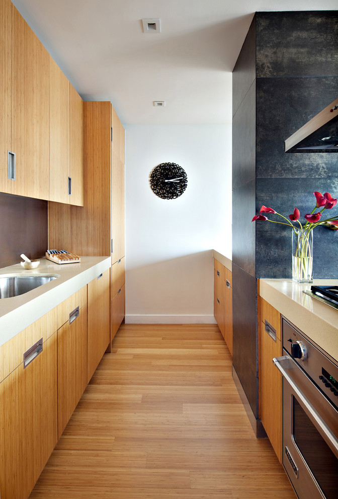 Zweizeilige, Offene, Mittelgroße Moderne Küche mit Küchengeräten aus Edelstahl, flächenbündigen Schrankfronten, hellbraunen Holzschränken, Unterbauwaschbecken und braunem Holzboden in New York