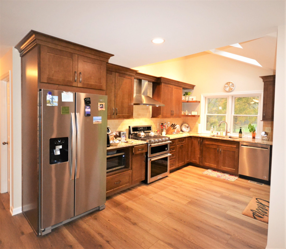 This is an example of a large traditional l-shaped kitchen/diner in Philadelphia with a double-bowl sink, flat-panel cabinets, medium wood cabinets, granite worktops, beige splashback, metro tiled splashback, stainless steel appliances, vinyl flooring, beige floors, beige worktops, a drop ceiling and a breakfast bar.