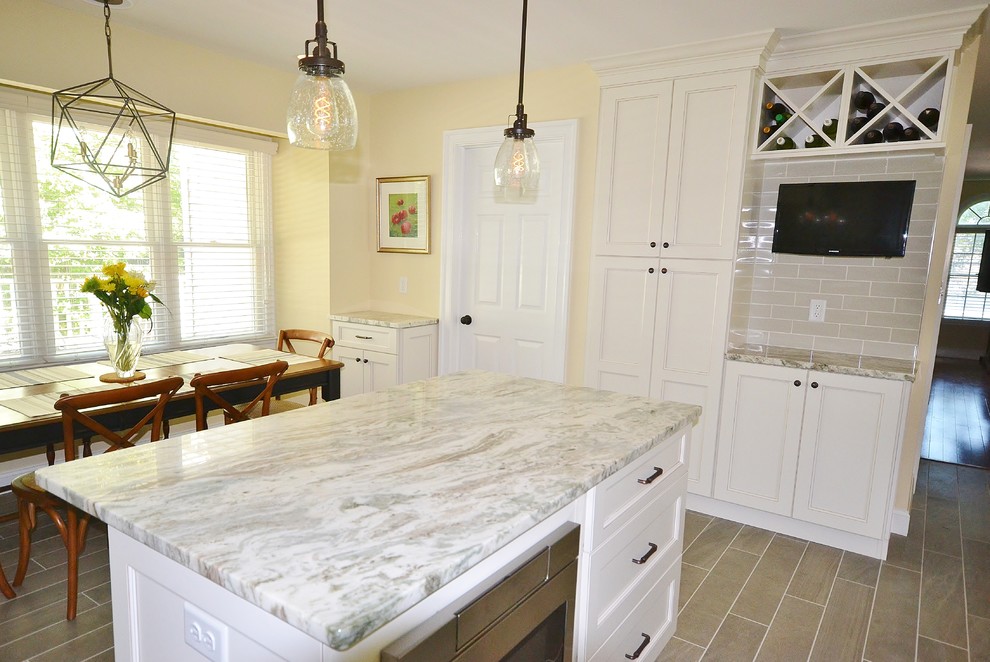 Exempel på ett stort klassiskt beige beige kök, med en undermonterad diskho, luckor med infälld panel, vita skåp, granitbänkskiva, vitt stänkskydd, stänkskydd i tunnelbanekakel, rostfria vitvaror, klinkergolv i keramik, en köksö och brunt golv