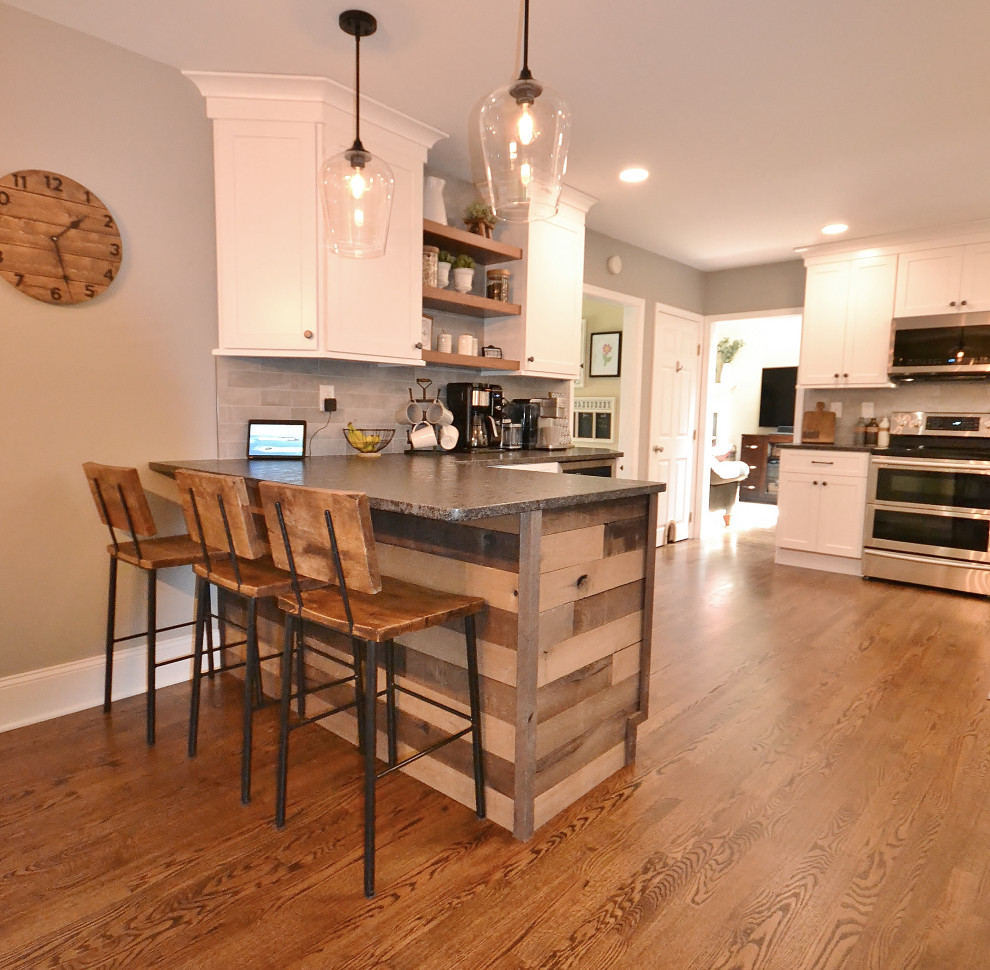 Exempel på ett stort klassiskt grå grått kök, med en rustik diskho, luckor med infälld panel, vita skåp, granitbänkskiva, grått stänkskydd, stänkskydd i tunnelbanekakel, rostfria vitvaror, ljust trägolv, en halv köksö och brunt golv
