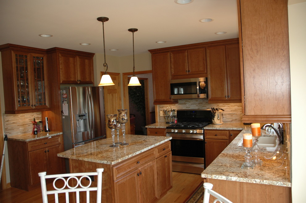 Klassisk inredning av ett mellanstort kök, med en undermonterad diskho, luckor med infälld panel, skåp i ljust trä, granitbänkskiva, beige stänkskydd, stänkskydd i mosaik, rostfria vitvaror, mellanmörkt trägolv och en köksö