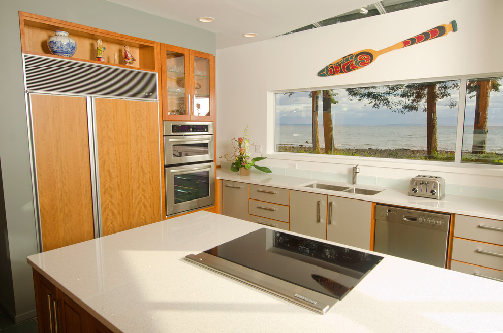 Imagen de cocinas en L minimalista con armarios con paneles lisos, puertas de armario grises, salpicadero azul, salpicadero de azulejos de vidrio y electrodomésticos con paneles