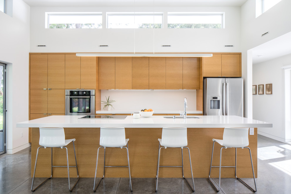 Inspiration for a mid-sized modern galley concrete floor and gray floor open concept kitchen remodel in Seattle with flat-panel cabinets, white backsplash, stainless steel appliances, an island, an undermount sink and medium tone wood cabinets
