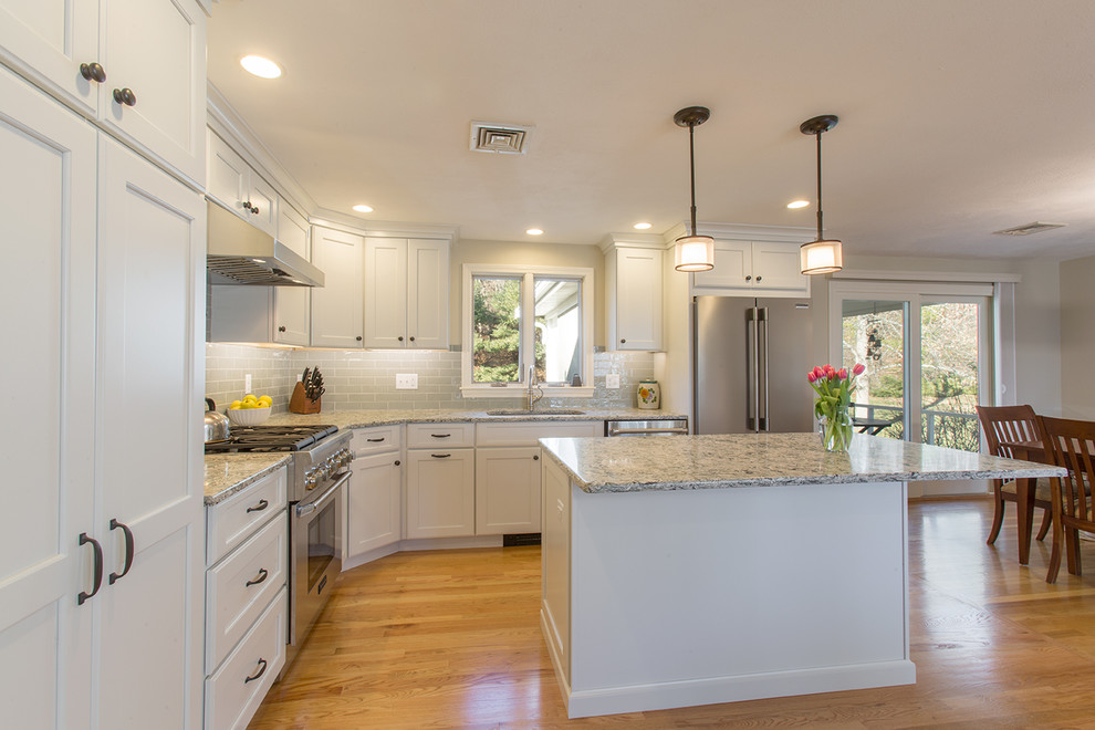 Medium sized traditional l-shaped kitchen/diner in Boston with a submerged sink, recessed-panel cabinets, white cabinets, engineered stone countertops, green splashback, ceramic splashback, stainless steel appliances, medium hardwood flooring and an island.