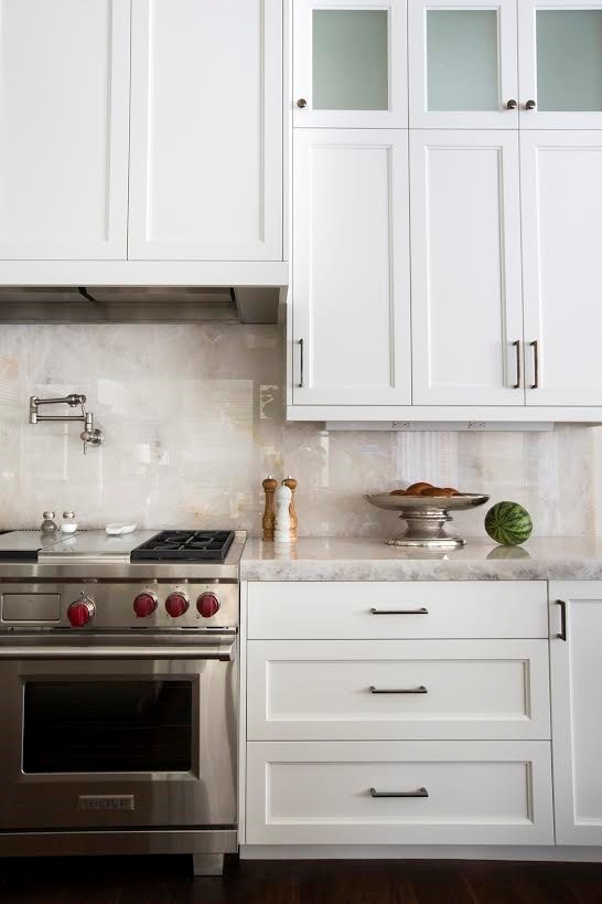 Klassisk inredning av ett avskilt, mellanstort kök, med en undermonterad diskho, luckor med infälld panel, vita skåp, bänkskiva i kvarts, vitt stänkskydd, stänkskydd i sten, rostfria vitvaror, mörkt trägolv, en köksö och brunt golv