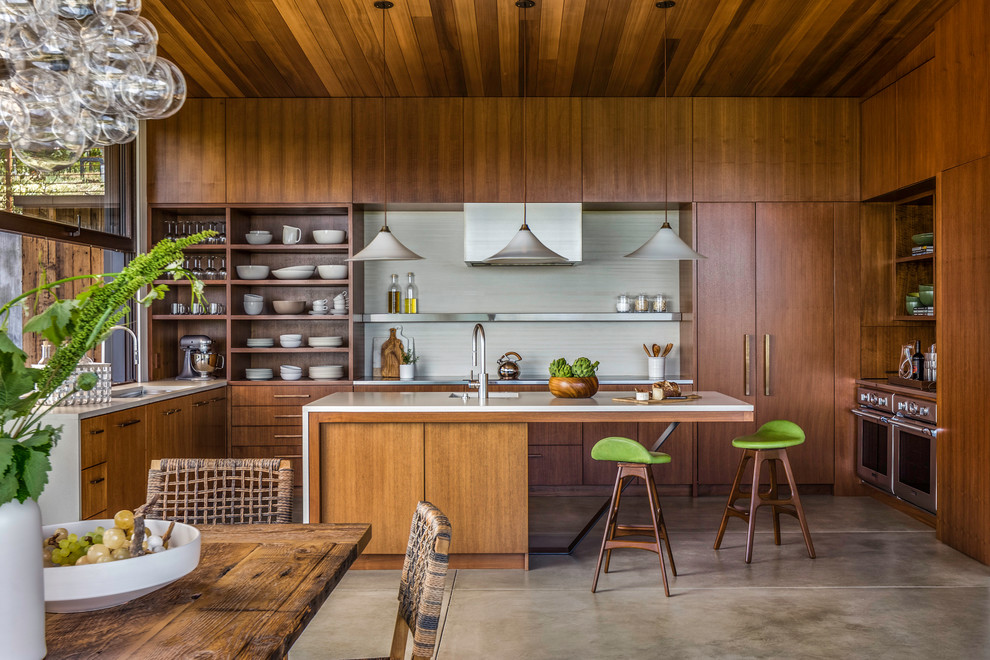 Inspiration for a contemporary u-shaped concrete floor and gray floor eat-in kitchen remodel in San Francisco with flat-panel cabinets, medium tone wood cabinets, white backsplash, an island and paneled appliances