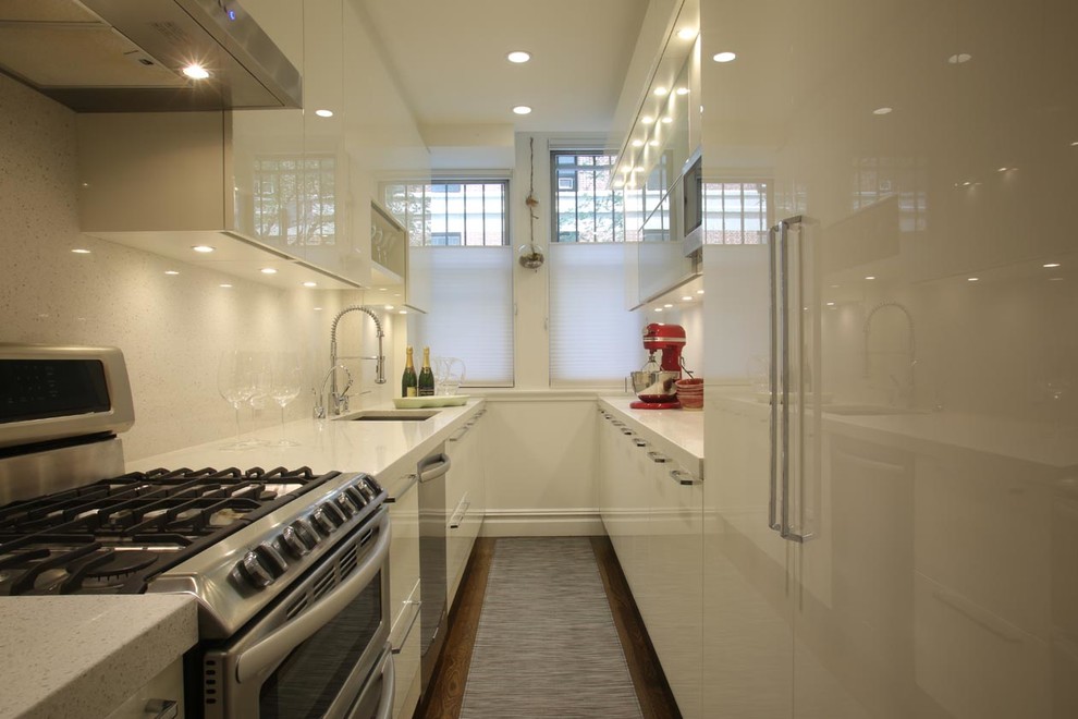 Photo of a medium sized modern galley enclosed kitchen in New York with a submerged sink, flat-panel cabinets, white cabinets, stainless steel appliances, medium hardwood flooring, no island, terrazzo worktops, white splashback and stone tiled splashback.
