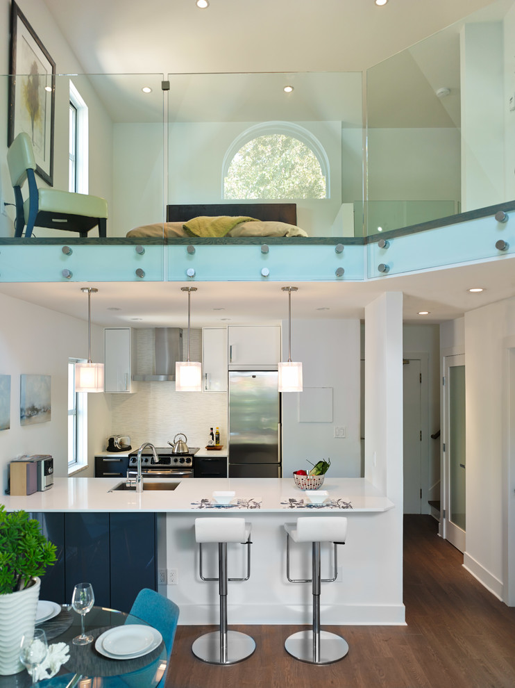 Contemporary galley open plan kitchen in Vancouver with a submerged sink, flat-panel cabinets, white cabinets, stainless steel appliances, quartz worktops, white splashback and porcelain splashback.