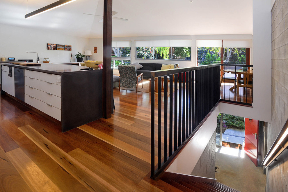Mittelgroße Moderne Küche mit weißen Schränken, Betonarbeitsplatte, braunem Holzboden, Kücheninsel, braunem Boden und schwarzer Arbeitsplatte in Townsville