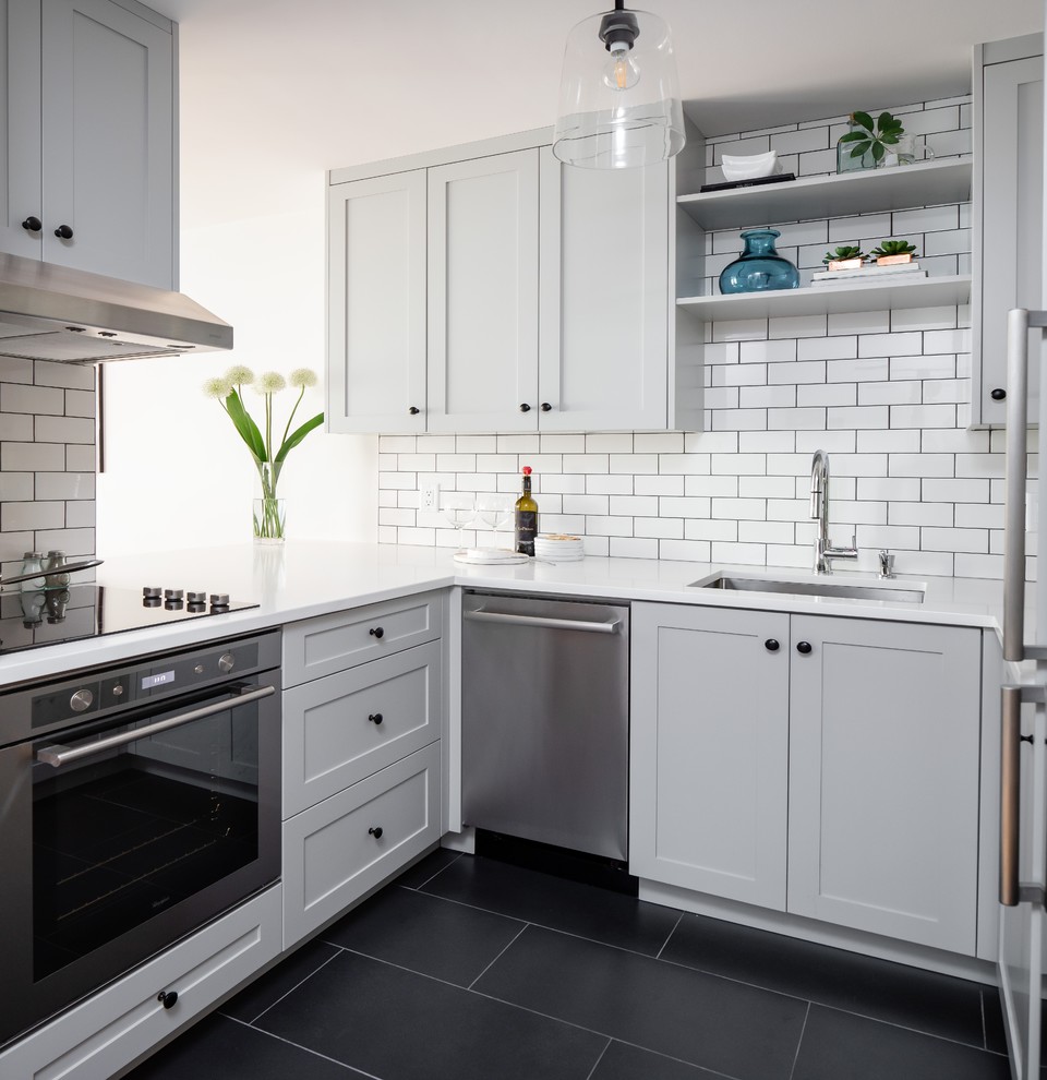 Foto på ett litet funkis vit u-kök, med en undermonterad diskho, skåp i shakerstil, grå skåp, vitt stänkskydd, stänkskydd i tunnelbanekakel, rostfria vitvaror, svart golv och bänkskiva i kvarts