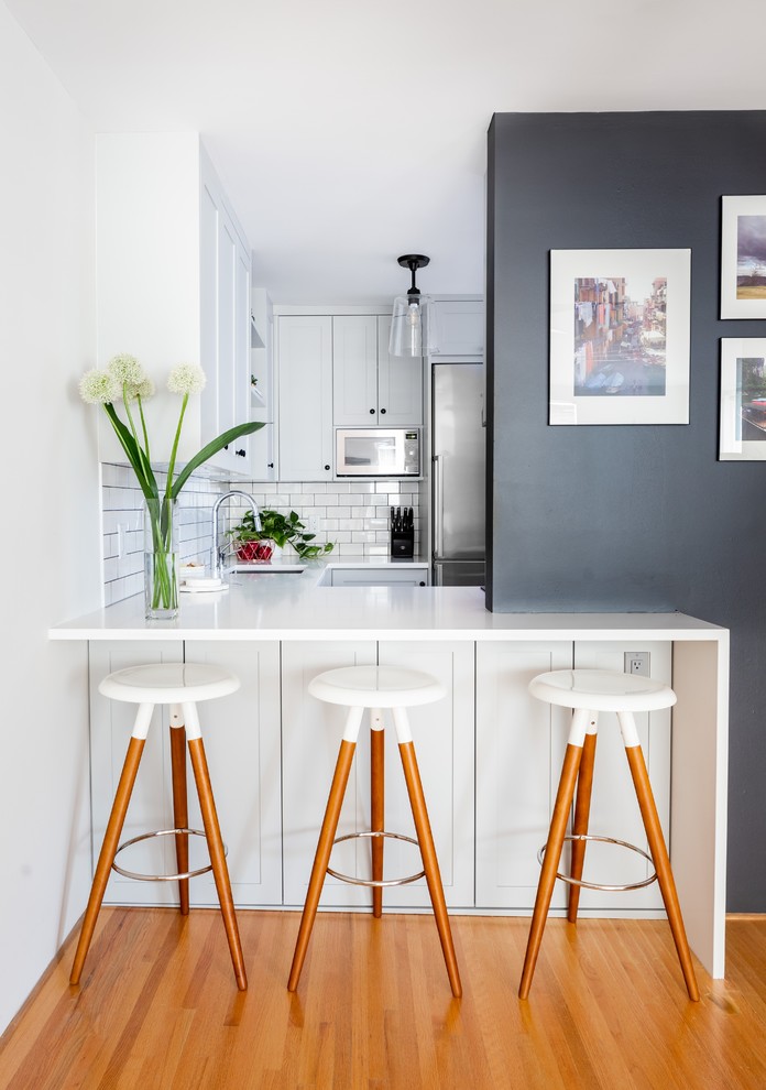 Modern inredning av ett litet vit vitt u-kök, med en undermonterad diskho, skåp i shakerstil, vitt stänkskydd, stänkskydd i tunnelbanekakel, rostfria vitvaror, grå skåp, bänkskiva i kvarts och svart golv
