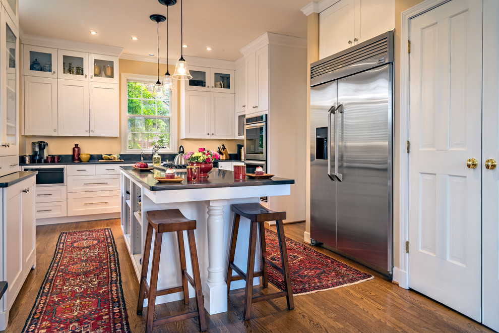Example of a large transitional u-shaped medium tone wood floor and brown floor open concept kitchen design in Nashville with an undermount sink, shaker cabinets, white cabinets, soapstone countertops, black backsplash, stone slab backsplash, stainless steel appliances, an island and black countertops