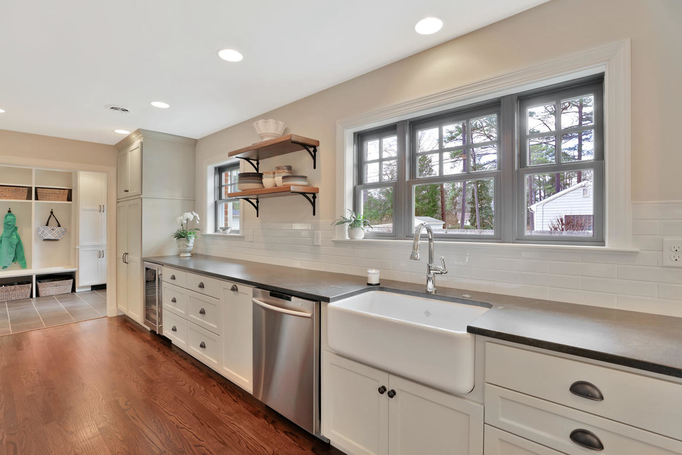 Eat-in kitchen - mid-sized farmhouse l-shaped dark wood floor and brown floor eat-in kitchen idea in Richmond with a farmhouse sink, shaker cabinets, white cabinets, solid surface countertops, white backsplash, subway tile backsplash, stainless steel appliances and an island