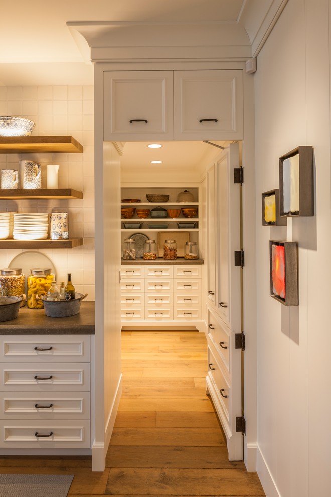 Modelo de cocina contemporánea con armarios con paneles empotrados, puertas de armario blancas, encimera de esteatita, salpicadero blanco, salpicadero de azulejos de cerámica y suelo de madera en tonos medios