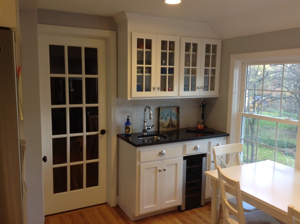 Aménagement d'une cuisine contemporaine en L avec un placard à porte vitrée, des portes de placard blanches, un électroménager en acier inoxydable, un sol en bois brun et îlot.