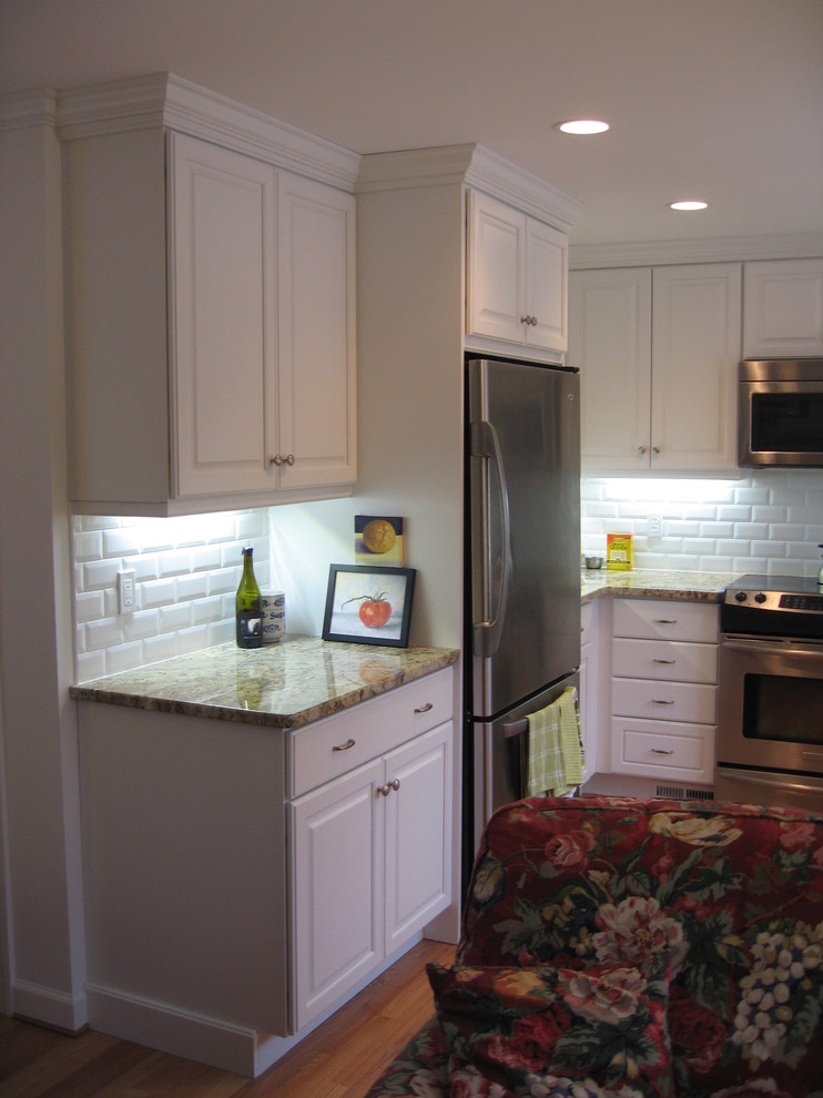 Inspiration for a small timeless u-shaped light wood floor enclosed kitchen remodel in Bridgeport with an undermount sink, raised-panel cabinets, white cabinets, granite countertops, white backsplash, subway tile backsplash, stainless steel appliances and no island