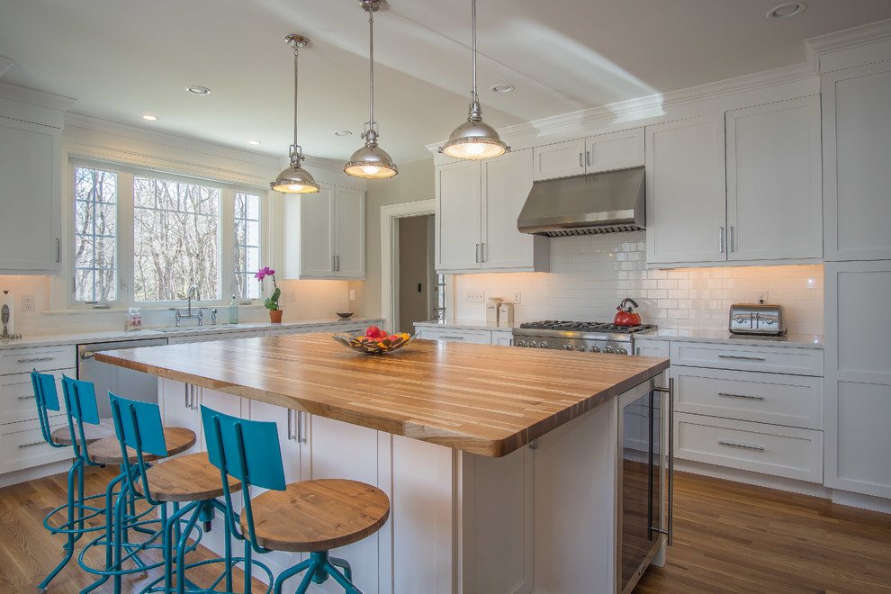 Inspiration for a large farmhouse l-shaped kitchen/diner in Bridgeport with a submerged sink, shaker cabinets, white cabinets, engineered stone countertops, white splashback, metro tiled splashback, stainless steel appliances, medium hardwood flooring, an island and green floors.