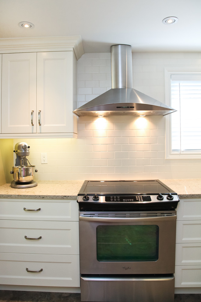 Example of a mid-sized transitional l-shaped eat-in kitchen design in Toronto with a double-bowl sink, recessed-panel cabinets, white cabinets, quartz countertops, white backsplash, subway tile backsplash, stainless steel appliances and a peninsula