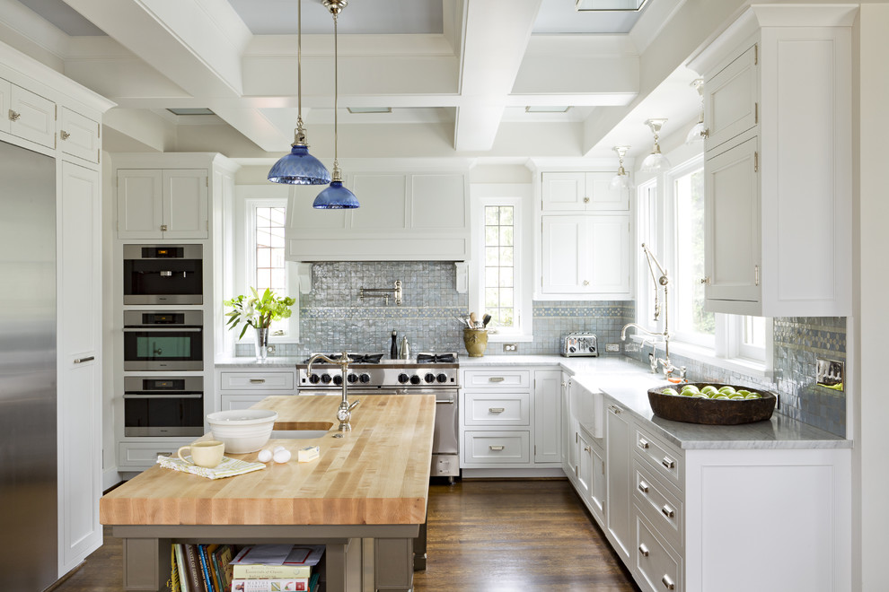 Elegant kitchen photo in Portland with stainless steel appliances, wood countertops, a farmhouse sink, recessed-panel cabinets, white cabinets and blue backsplash