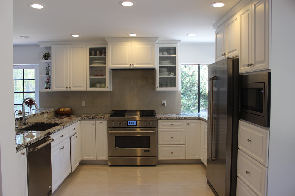 Inspiration for a mid-sized modern u-shaped porcelain tile kitchen remodel in Los Angeles with an undermount sink, raised-panel cabinets, white cabinets, granite countertops, beige backsplash, porcelain backsplash, stainless steel appliances and a peninsula