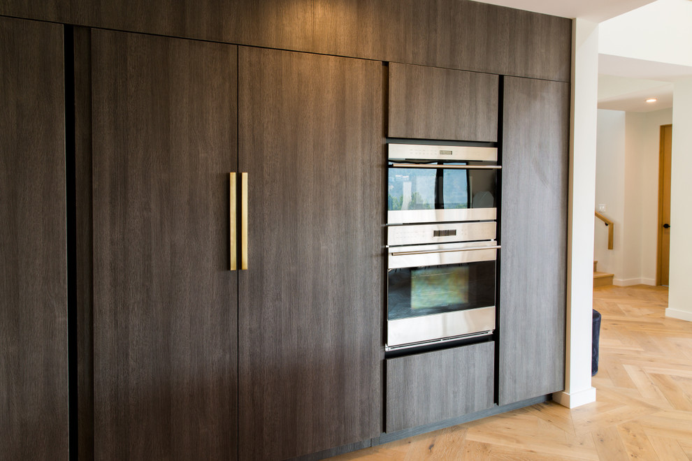 Huge minimalist u-shaped light wood floor open concept kitchen photo in Los Angeles with an undermount sink, flat-panel cabinets, dark wood cabinets, marble countertops, white backsplash, marble backsplash, stainless steel appliances, an island and white countertops