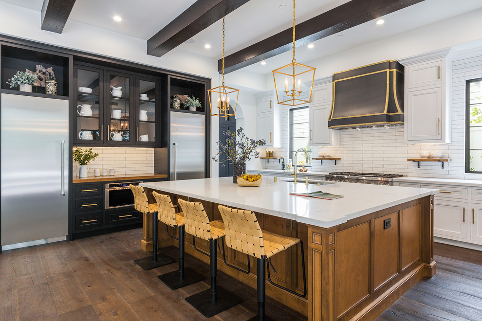Inspiration for a traditional kitchen in Los Angeles with a submerged sink, recessed-panel cabinets, white cabinets, white splashback, stainless steel appliances, dark hardwood flooring, an island and brown floors.