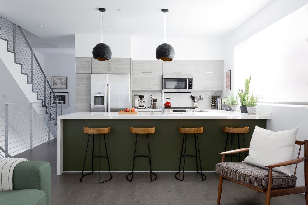 Cette image montre une cuisine parallèle et bicolore design avec un évier encastré, un placard à porte plane, des portes de placard grises, îlot et un sol gris.