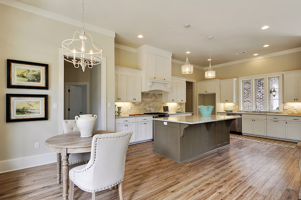 Inspiration for a large classic u-shaped open plan kitchen in New Orleans with a submerged sink, shaker cabinets, white cabinets, beige splashback, metro tiled splashback, stainless steel appliances, medium hardwood flooring and an island.