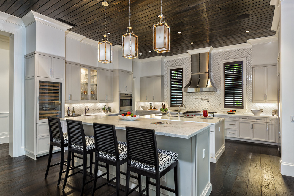 Klassische Küche in U-Form mit Unterbauwaschbecken, Schrankfronten mit vertiefter Füllung, beigen Schränken, Küchenrückwand in Grau, Küchengeräten aus Edelstahl, dunklem Holzboden und zwei Kücheninseln in Miami