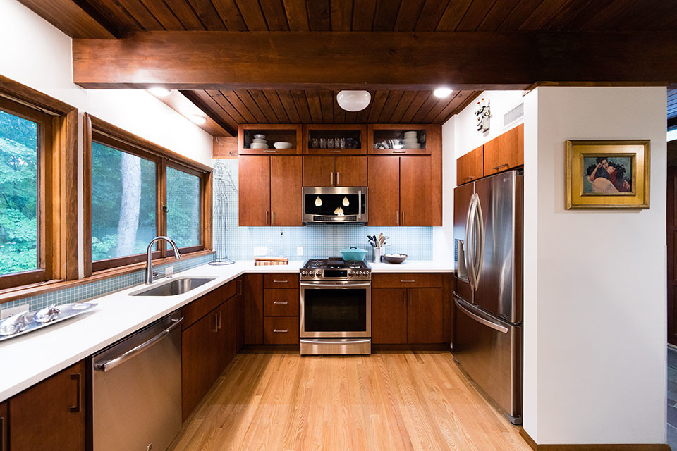 Example of a mid-century modern u-shaped medium tone wood floor and brown floor open concept kitchen design in Other with an undermount sink, flat-panel cabinets, medium tone wood cabinets, quartz countertops, blue backsplash, mosaic tile backsplash, stainless steel appliances, no island and white countertops