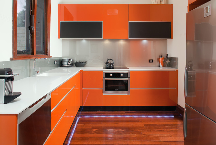 Modern inredning av ett mellanstort grå grått kök, med en integrerad diskho, släta luckor, orange skåp, bänkskiva i koppar, stänkskydd med metallisk yta, glaspanel som stänkskydd, rostfria vitvaror och mörkt trägolv