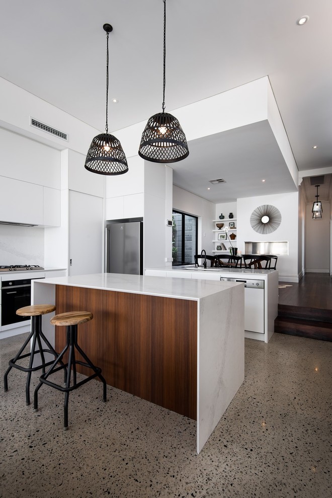 Bild på ett mellanstort funkis kök, med vita skåp, vitt stänkskydd, stänkskydd i sten, betonggolv, en köksö, en undermonterad diskho, bänkskiva i kvarts och rostfria vitvaror