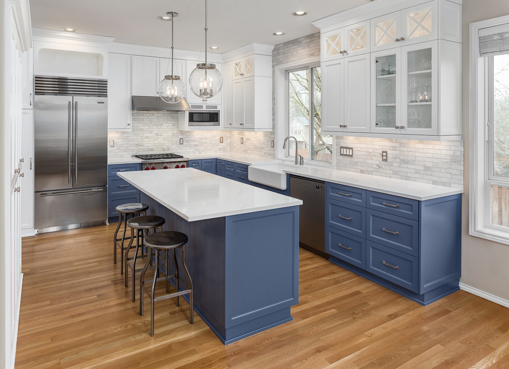 Mid-sized transitional l-shaped porcelain tile eat-in kitchen photo in Portland with a farmhouse sink, recessed-panel cabinets, blue cabinets, quartz countertops, white backsplash, marble backsplash, stainless steel appliances and an island