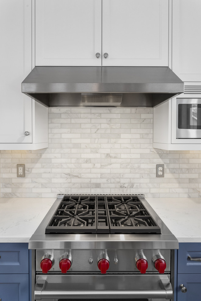 Example of a mid-sized classic l-shaped porcelain tile eat-in kitchen design in Portland with a farmhouse sink, recessed-panel cabinets, blue cabinets, quartz countertops, white backsplash, marble backsplash, stainless steel appliances and an island