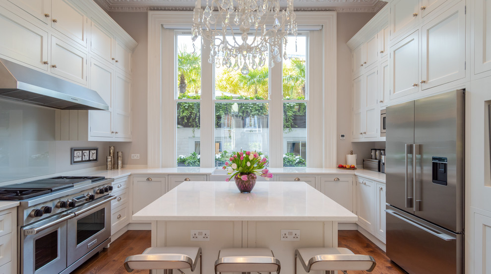 Exempel på ett stort klassiskt vit vitt u-kök, med en rustik diskho, skåp i shakerstil, vita skåp, glaspanel som stänkskydd, rostfria vitvaror, mellanmörkt trägolv, en köksö och brunt golv