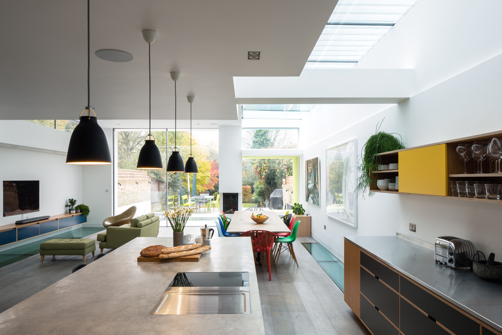 Diseño de cocinas en L moderna, abierta, con encimera de cemento, electrodomésticos de acero inoxidable y una isla