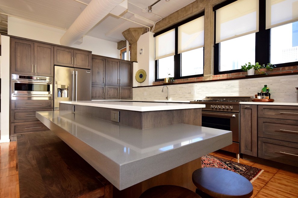Inspiration for a large industrial u-shaped medium tone wood floor and brown floor eat-in kitchen remodel in Chicago with a drop-in sink, recessed-panel cabinets, dark wood cabinets, granite countertops, white backsplash, terra-cotta backsplash, stainless steel appliances and an island