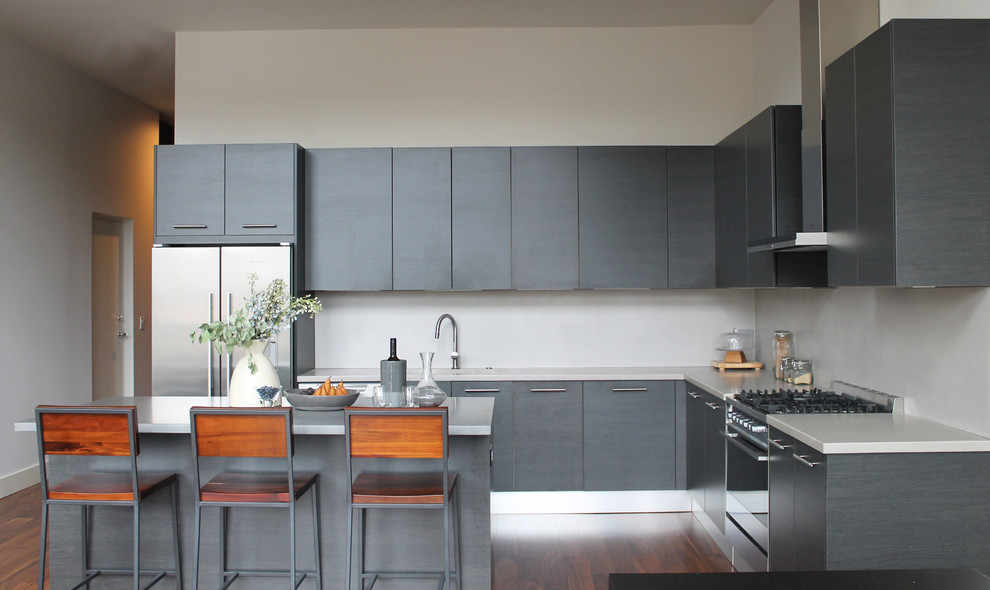 Moderne Küche in L-Form mit integriertem Waschbecken, flächenbündigen Schrankfronten, grauen Schränken, Küchengeräten aus Edelstahl, dunklem Holzboden, Kücheninsel und Betonarbeitsplatte in Chicago