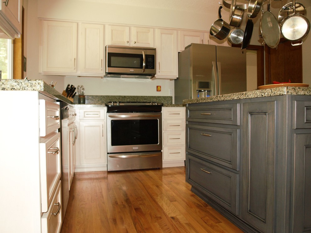 Bild på ett litet vintage u-kök, med en undermonterad diskho, luckor med infälld panel, vita skåp, granitbänkskiva, grått stänkskydd, stänkskydd i stenkakel, rostfria vitvaror och ljust trägolv