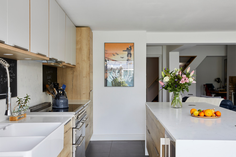 Geschlossene, Zweizeilige, Mittelgroße Moderne Küche mit Landhausspüle, flächenbündigen Schrankfronten, hellen Holzschränken, Quarzit-Arbeitsplatte, Küchenrückwand in Weiß, Keramikboden, Kücheninsel, grauem Boden und weißer Arbeitsplatte in London