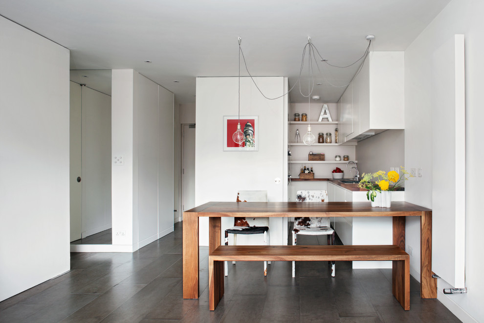 Modern inredning av ett litet kök, med betonggolv, en nedsänkt diskho, öppna hyllor, vita skåp och träbänkskiva