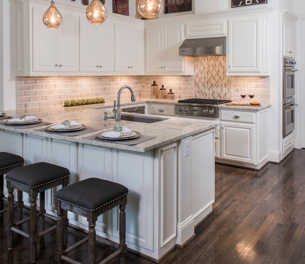 Example of a mid-sized transitional u-shaped medium tone wood floor and brown floor eat-in kitchen design in Dallas with an undermount sink, raised-panel cabinets, white cabinets, stainless steel appliances, granite countertops, brown backsplash, glass tile backsplash and no island