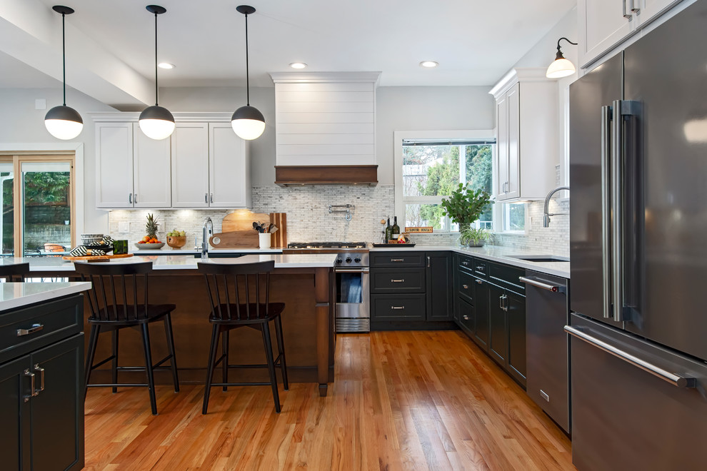 This is an example of a medium sized traditional l-shaped kitchen/diner in Seattle with a submerged sink, flat-panel cabinets, green cabinets, engineered stone countertops, white splashback, marble splashback, stainless steel appliances, medium hardwood flooring, an island, brown floors and white worktops.