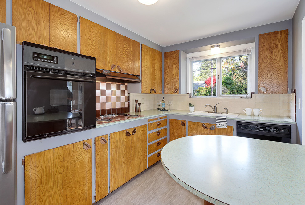 シアトルにある小さなミッドセンチュリースタイルのおしゃれなキッチン (中間色木目調キャビネット、ラミネートカウンター、緑のキッチンカウンター) の写真
