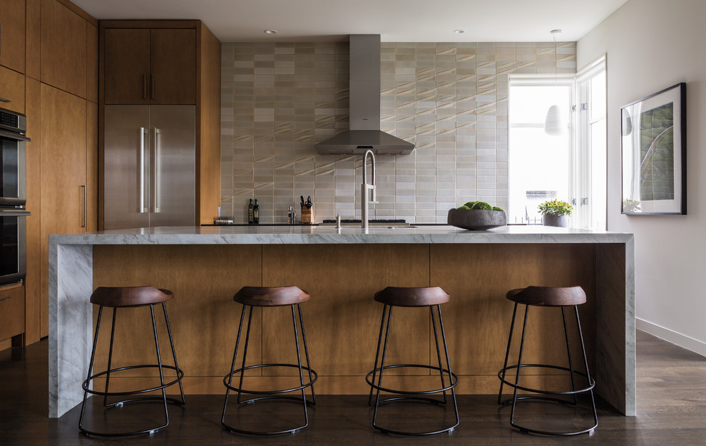 Cette photo montre une cuisine tendance en bois brun avec un placard à porte plane, une crédence grise, un électroménager en acier inoxydable, parquet foncé et îlot.